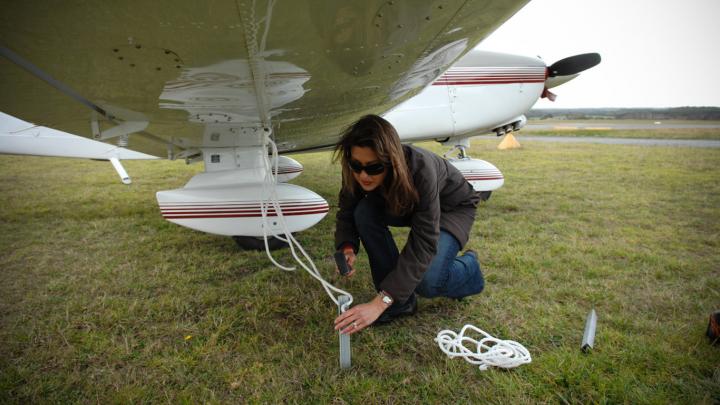 Pilot hammering stake to tie down aircraft